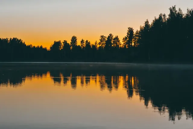 Auringonlasku metsäisen järven yllä