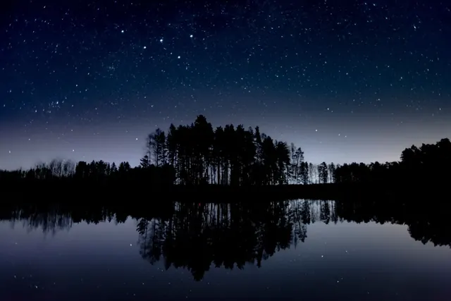 Tähtitaivas järven ja saaren yllä