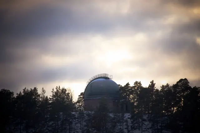 Observatorion kupoli metsän takana illan hämärässä